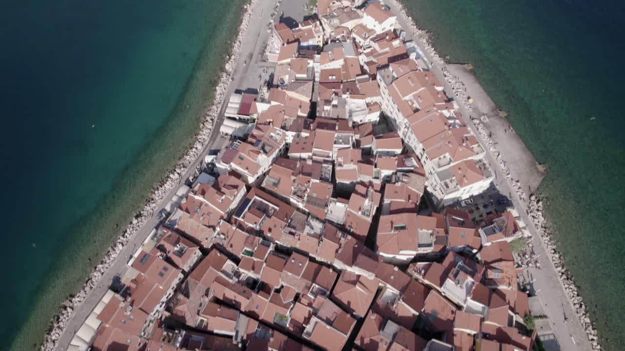 video de drones de una toma aérea anterior con panorámica descriptiva sobre el faro de la ciudad de piran en eslovenia, se pueden ver pájaros volando y el video termina en el horizonte del mar