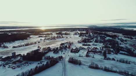aerial view of snowy winter christmas landscape far north nordic scandinavia swedish norwegian hills forest mountain top as sun sets late afternoon cold road empty wasteland lonely houses and homes