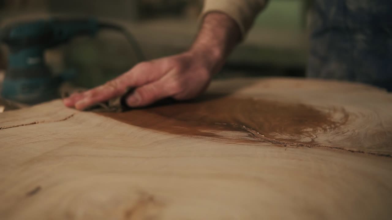 el carpintero con un trapo en la mano procesa la madera con aceite después de molerla.