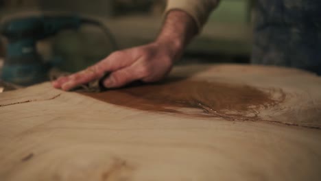 the carpenter with a rag in his hand processes the wood with oil after grindering. close up