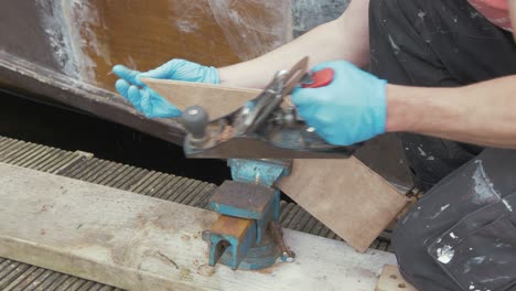 a carpenter planing a piece of plywood for a wooden boat