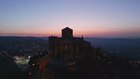 orbital drone footage of large red building at sunset in cardona in spain