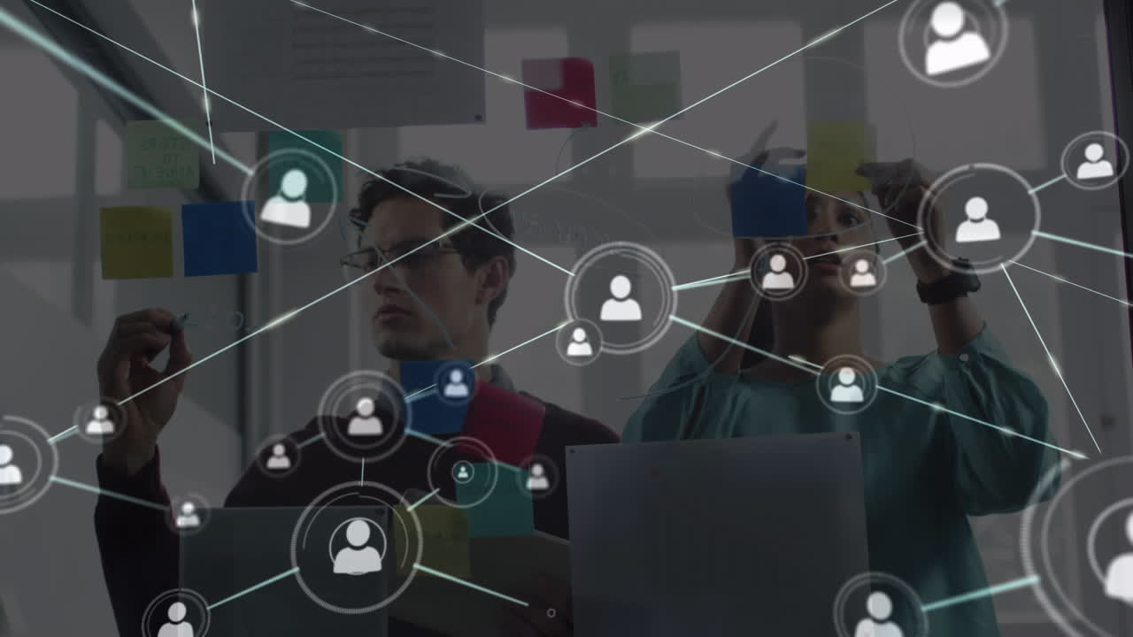 Animation of network of people icons over male and female colleague brainstorming in office