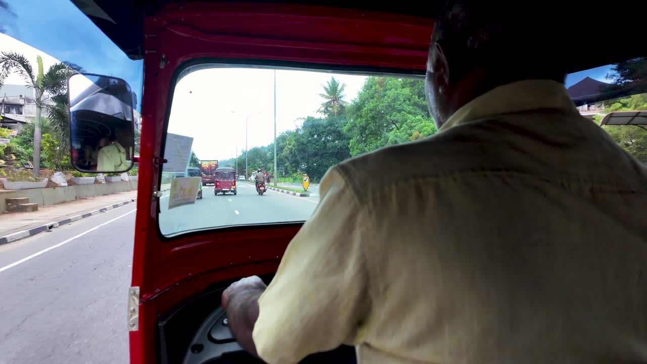 Tuk tuk driver skillfully navigating bustling city traffic in kandy, sri lanka on a vibrant day, showcasing fast paced asian transportation culture