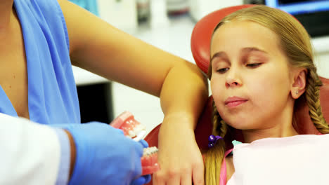 dentista mostrando a un paciente joven cómo cepillarse los dientes