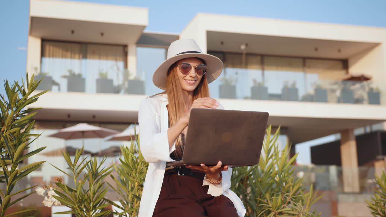 mujer trabajando en una computadora portátil al aire libre en una villa de lujo