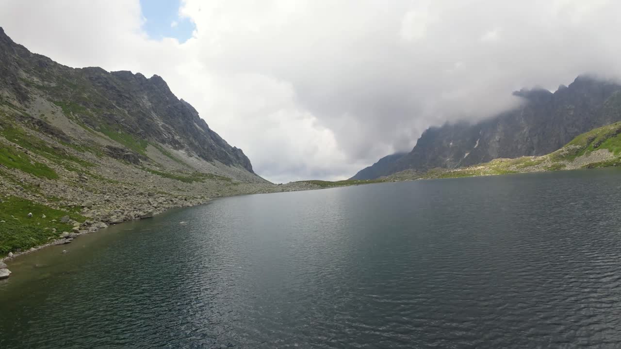 슬로바키아의 높은 타트라 산맥에 자리 잡은 안개가 가득한 산 호수를 포착하는 fpv 드론 비디오