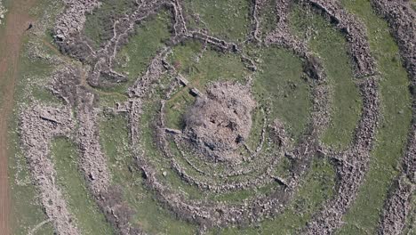 Top-view-pulling-away-over-ancient-circular-stone-structure-Rajum-el-hiri,-Israel