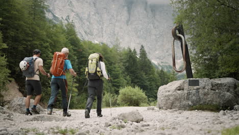 hikers walking past the camera forward towards the mountain past the climbing carabiner statue