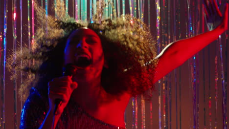 young woman with microphone singing at karaoke nightclub bar or disco with sparkling lights in background 4