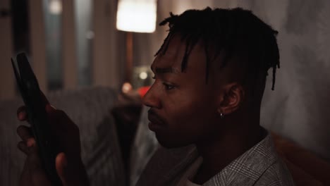 Young-black-male-concentrating-while-looking-at-his-tablet-device-at-home