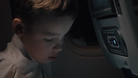 Boy-playing-chess-on-touch-pad-during-night-flight