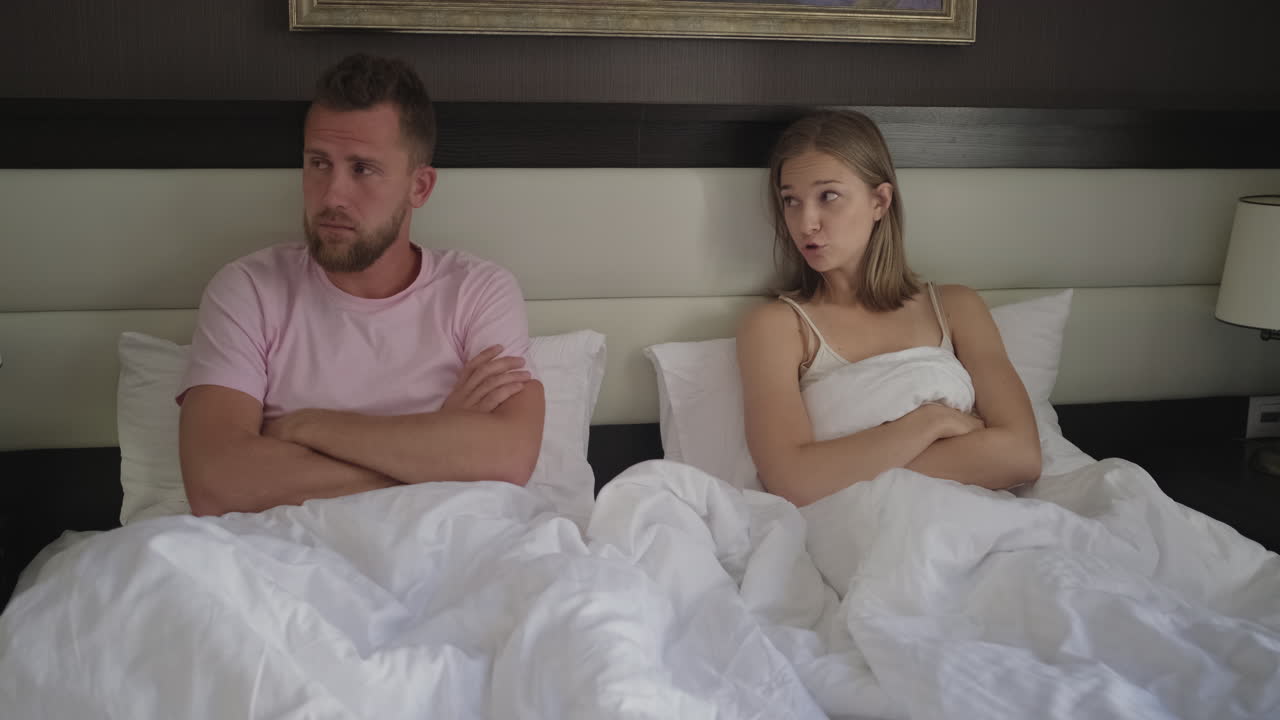 una pareja discutiendo en la cama.