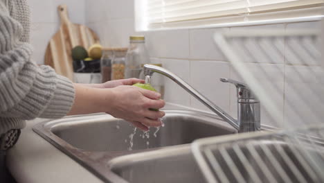 Manos-De-Mujer-Lavando-Una-Manzana-En-La-Cocina-A-Cámara-Lenta