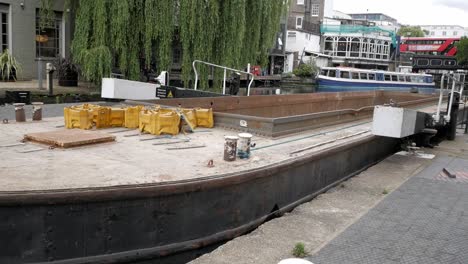 narrowboat with container for construction and industry transportation being pulled out of lock chamber at regent's canal