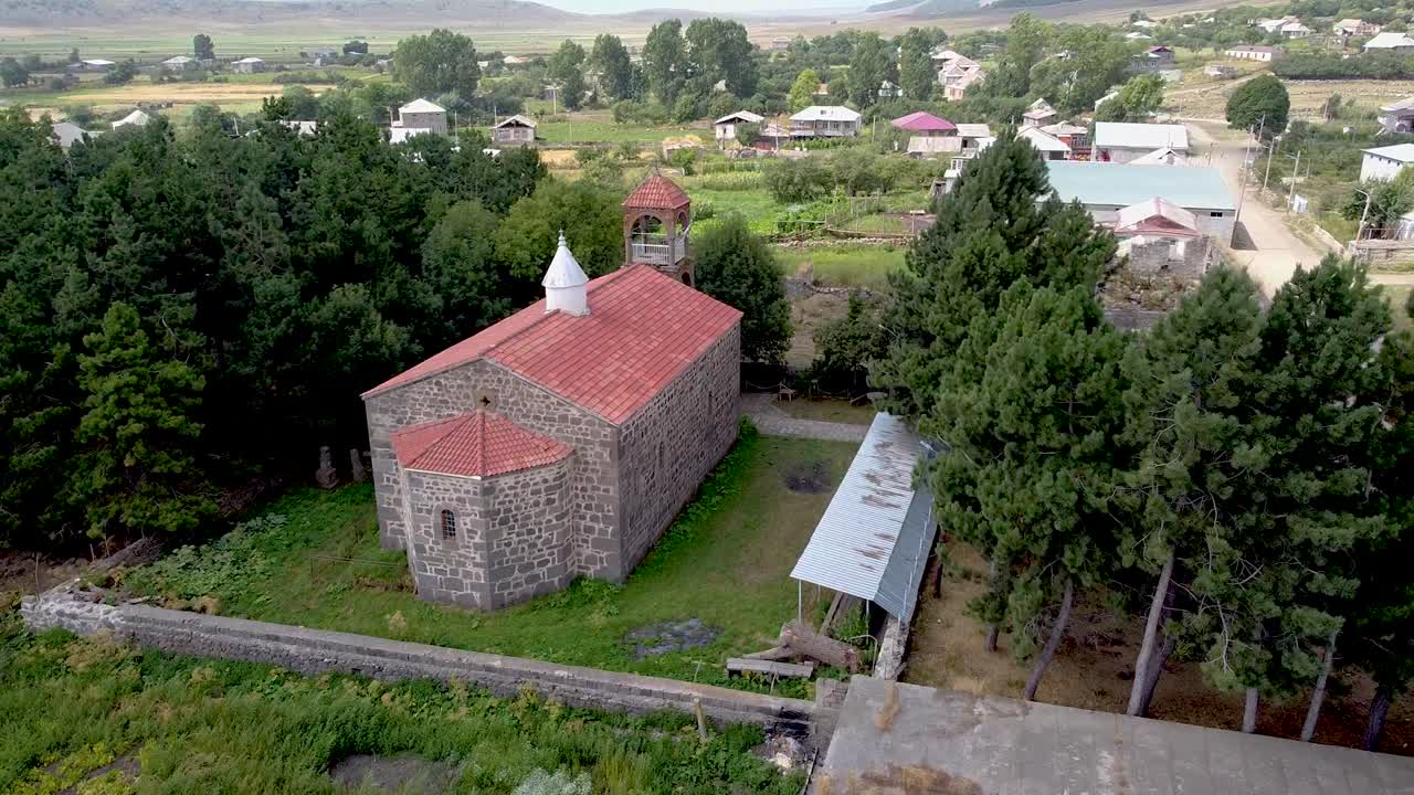 Explore the beauty of a historic stone church nestled in a serene village landscape. Lush greenery and rustic houses complete this peaceful setting