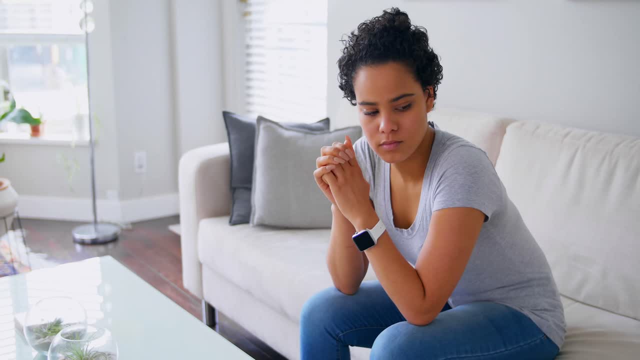Thoughtful woman sitting on the sofa in living room 4k