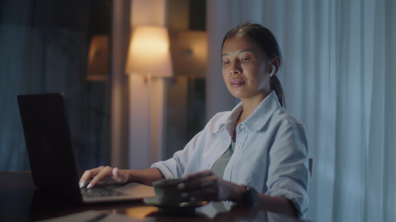 Asian Woman Working on Laptop in Evening at Home