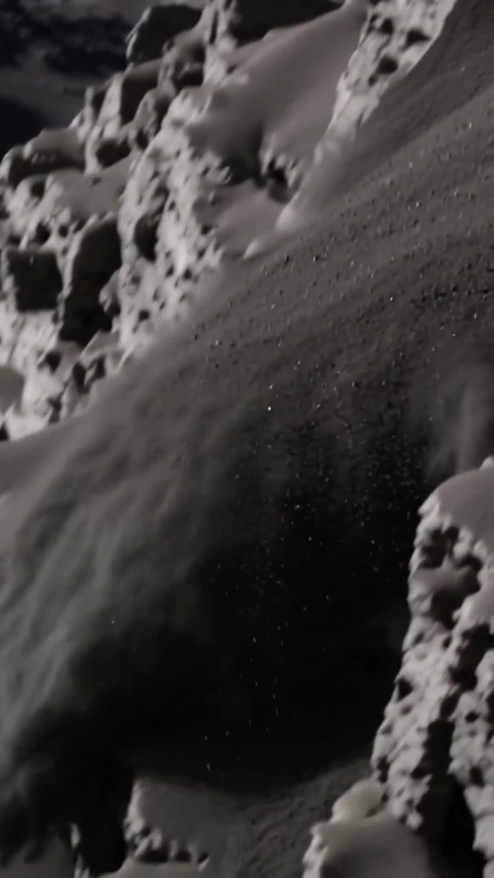 Video verticale: Foglio granulare che scivola giù per ripide sporgenze dopo uno scivolamento in alto a sinistra, formando una nuvola di polvere.