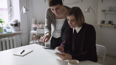 Junge-Frau-Sitzt-Am-Tisch-Und-Benutzt-Gemeinsam-Mit-Einem-Freund-Zu-Hause-Einen-Tablet-PC