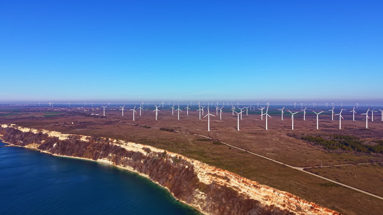 Aerogeradores em uma falésia com vista para o oceano perto de um parque eólico em uma paisagem de céu azul claro durante o dia