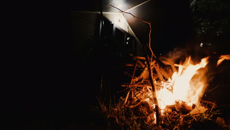 night shot of campfire burning in front of wooden bungalow