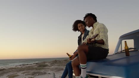 Man-playing-guitar-and-woman-singing-a-song-on-pickup-truck-bonnet-4k