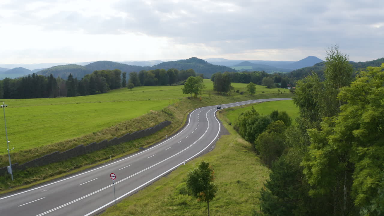 Auta jedoucí po dálnici v zelené travnaté krajině v Česku