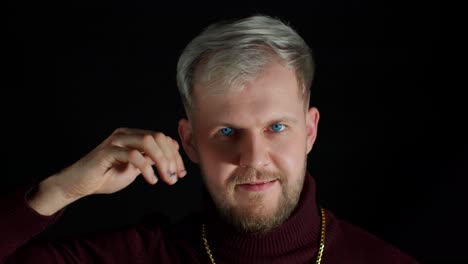 smiling man in stylish blouse looking approvingly at camera showing thumbs up on black background