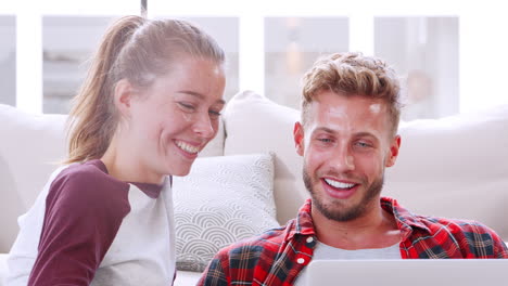 young couple at home talking and using laptop, close up