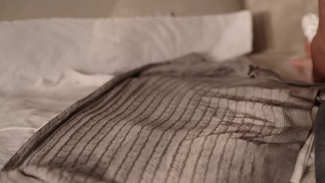 single father wrapping newborn baby boy into gray blanket on fluffy sofa in living room