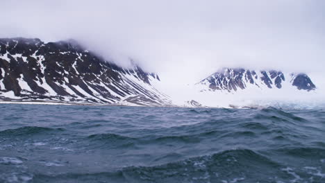 navegando a través de un glaciar y montañas nevadas en un yate en el ártico