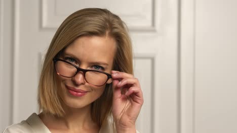 una hermosa modelo rubia con gafas hace un guiño a la cámara.