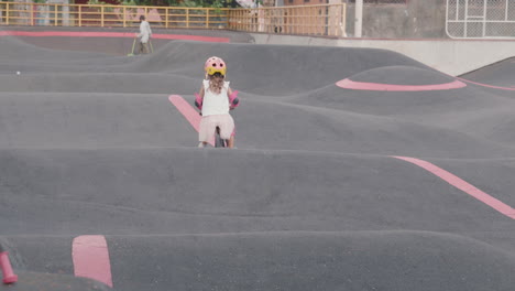 little girl riding a balance bike in a skate park