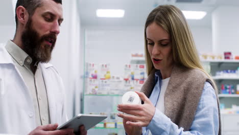hombre con tableta hablando con una mujer joven en la farmacia.