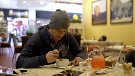 man having tasty dinner in cafe and using pad