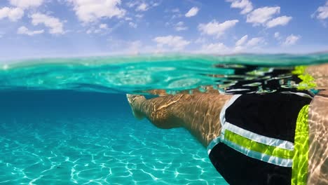 First-person-view-of-man-legs-and-feet-floating-on-breathtaking-clear-and-transparent-ocean-water-of-exotic-island