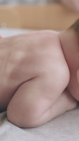 adorable infant boy with short blond hair lies on special table and enjoys professional back massage close view
