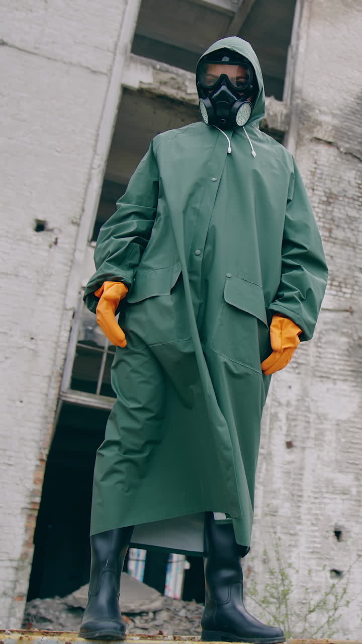 Person in protective suit standing in ruined city. Man in biohazard suit