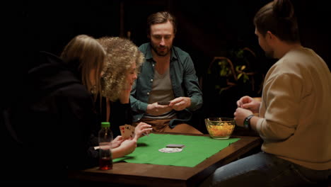grupo de amigos jugando al póquer sentados en sillas en una mesa en casa 6