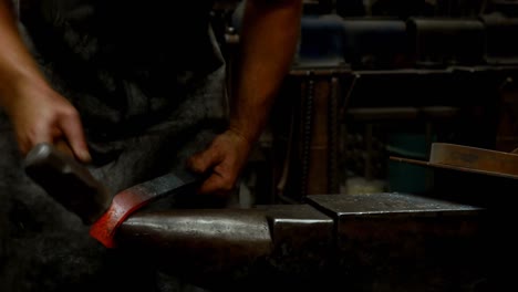 Blacksmith-shaping-a-metal-rod-in-workshop-4k