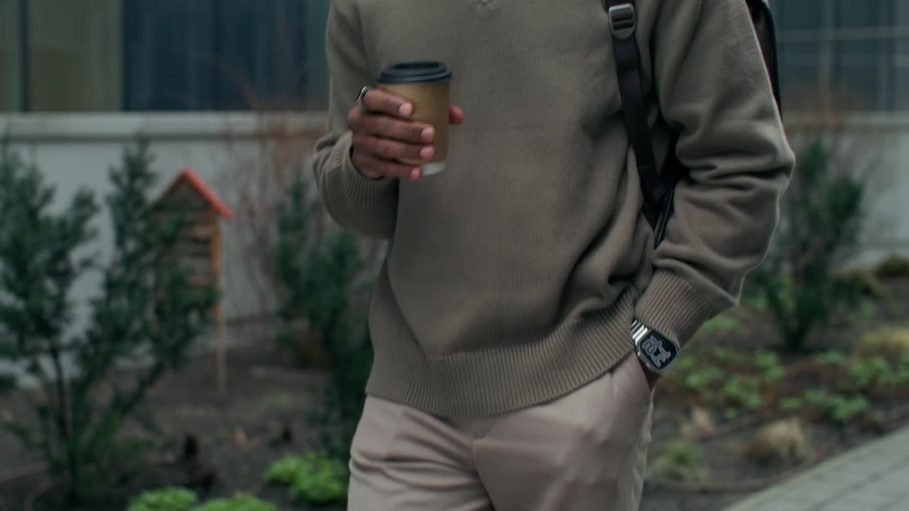 hombre caminando al aire libre con café y mochila