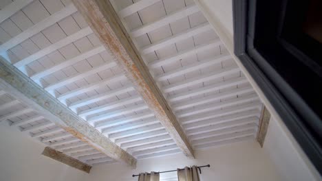 techo antiguo de vigas de madera con pintura astillada en una villa rústica en el sur de francia, mirando hacia la derecha