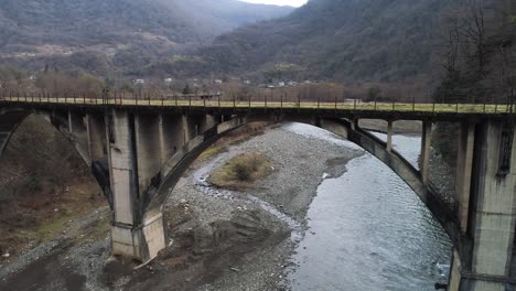 old concrete arch bridge over a mountain river