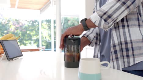 Mid-section-of-african-american-man-making-coffee-in-kitchen,-slow-motion