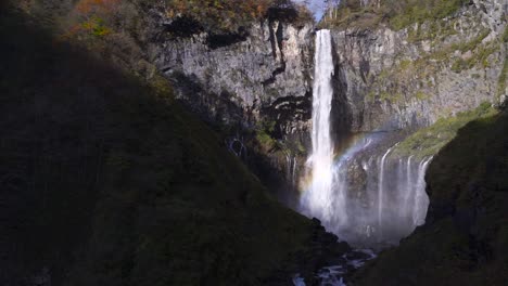 slow motion tilt up over beautiful kegon waterfalls in nikko with rainbow and autumn colors