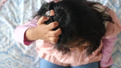 child touching their head on a bed