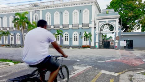 grand blue historic building with ornate gate and a cyclist on the street