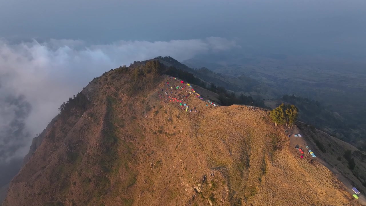 Campeggio con tende colorate sul bordo del cratere di un vulcano. Escursione alla cima del Monte Rinjani, Indonesia. Ripresa da drone.