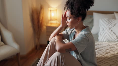 woman sitting on a bed looking thoughtful